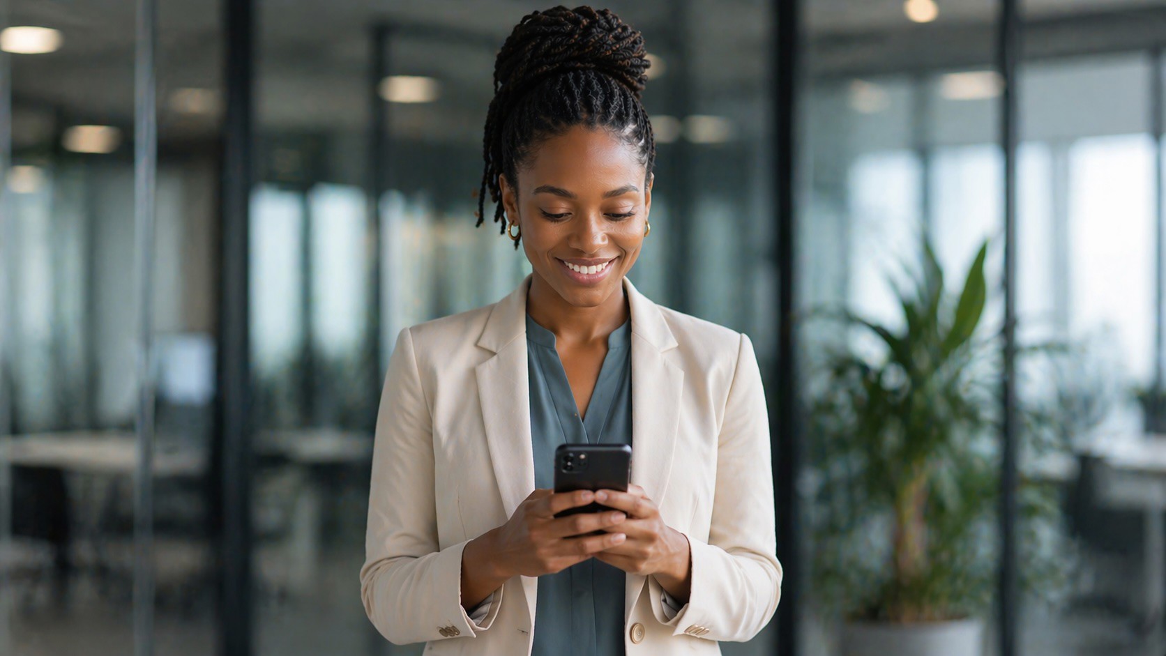 A young professional reading on her phone in a sunlit study
