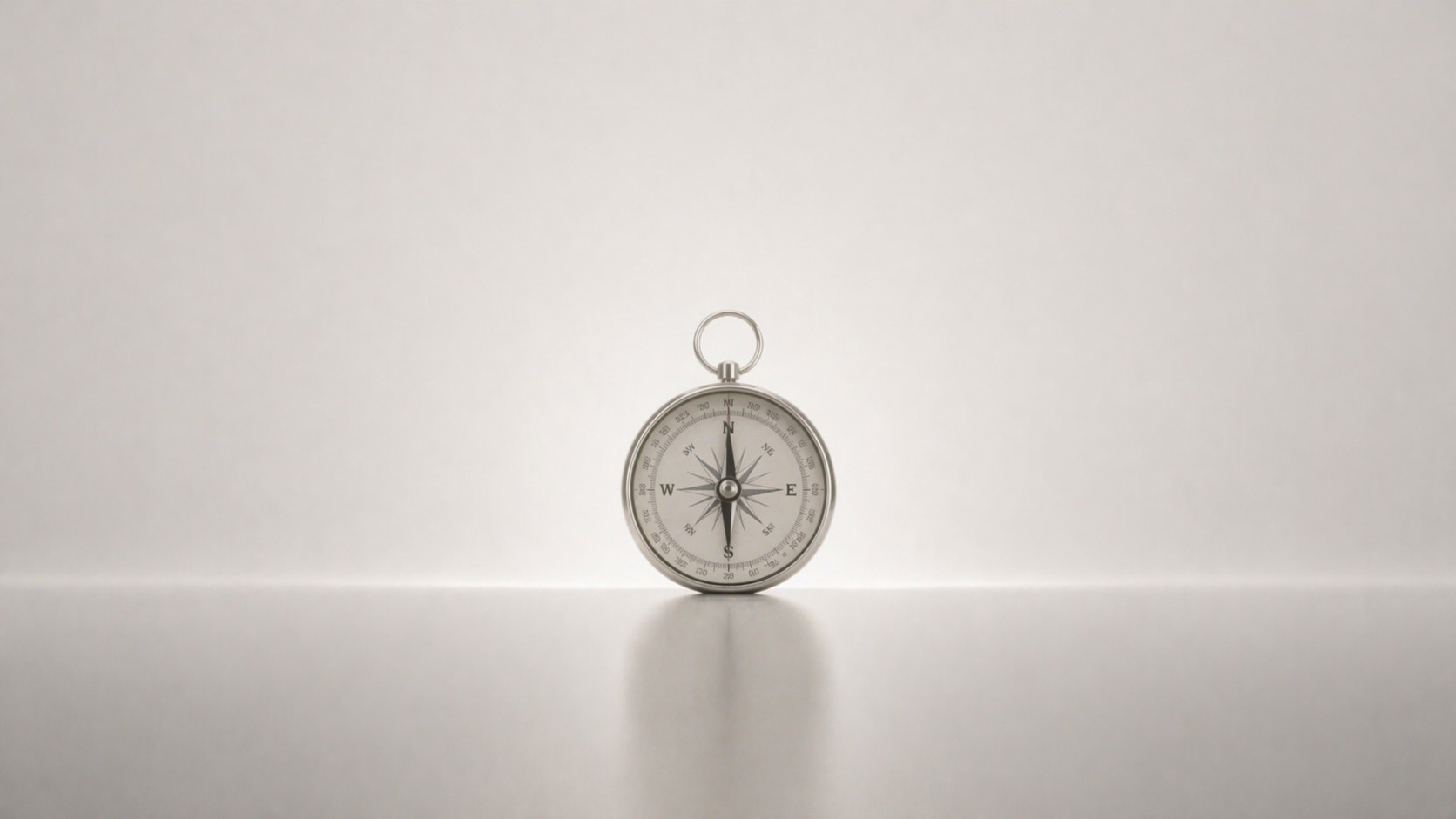 A silver compass resting on a softly lit surface